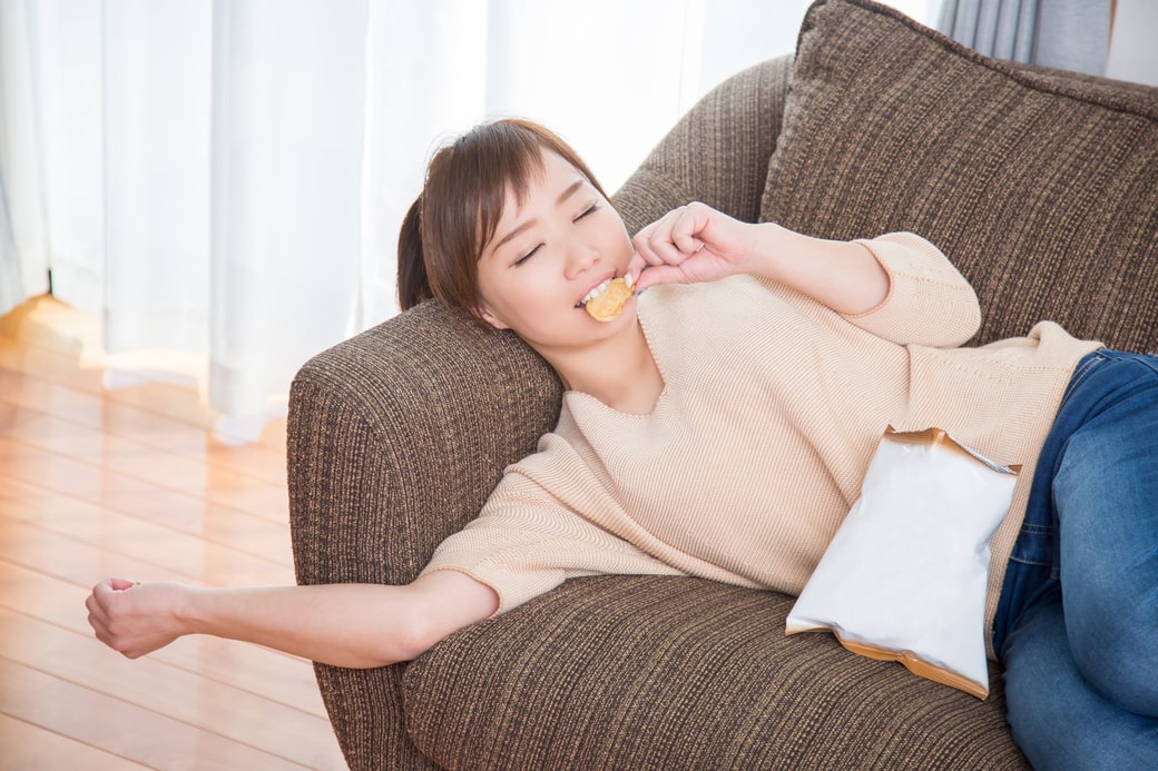 ソファでお菓子を食べる女性