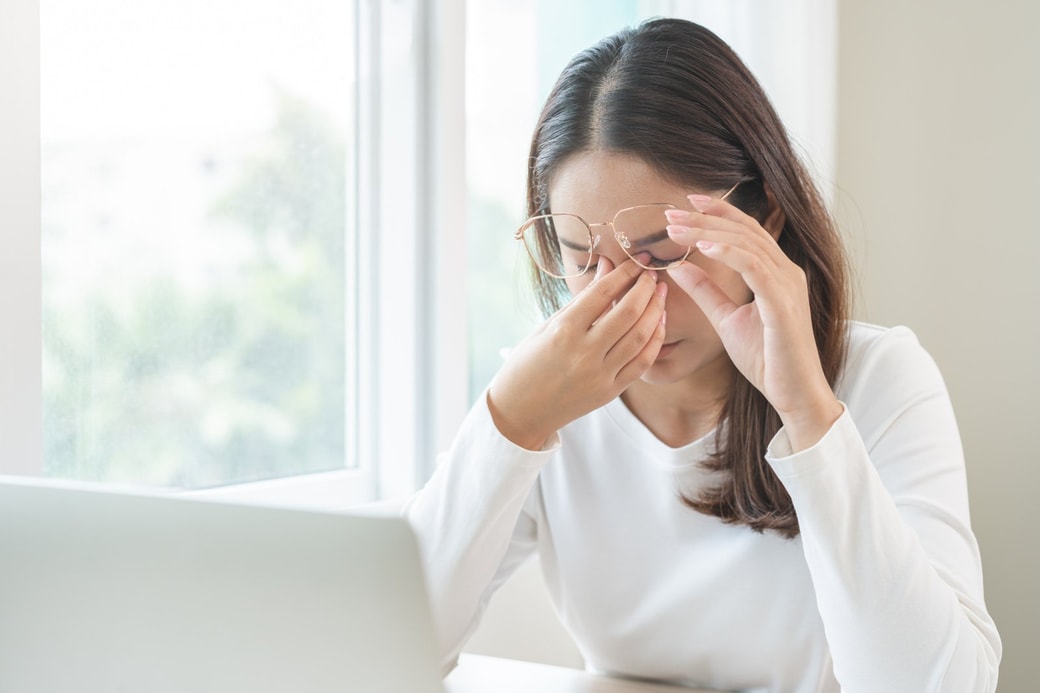PCの前で目を抑える女性
