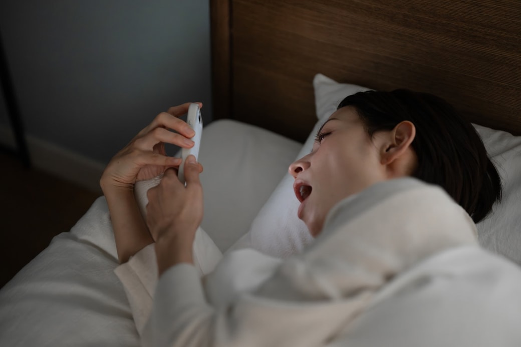 ベッドでスマホを見る女性
