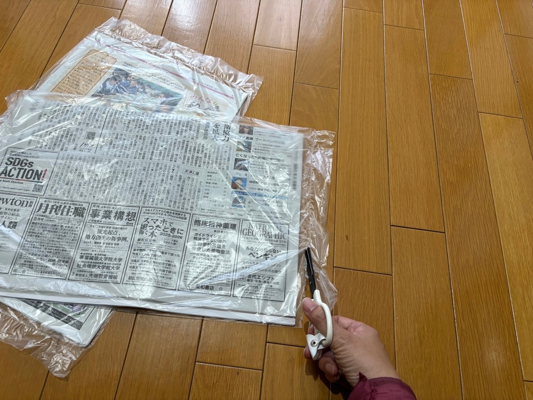 新聞ビニールをハサミで切る様子