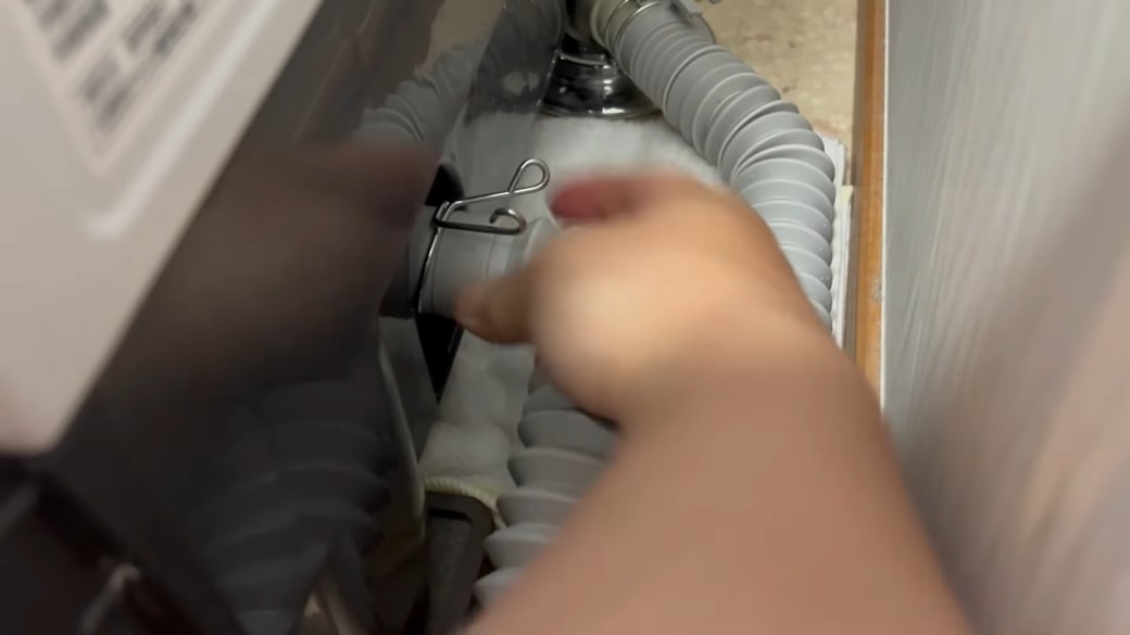 ドラム式洗濯機の排水ホースを外す人