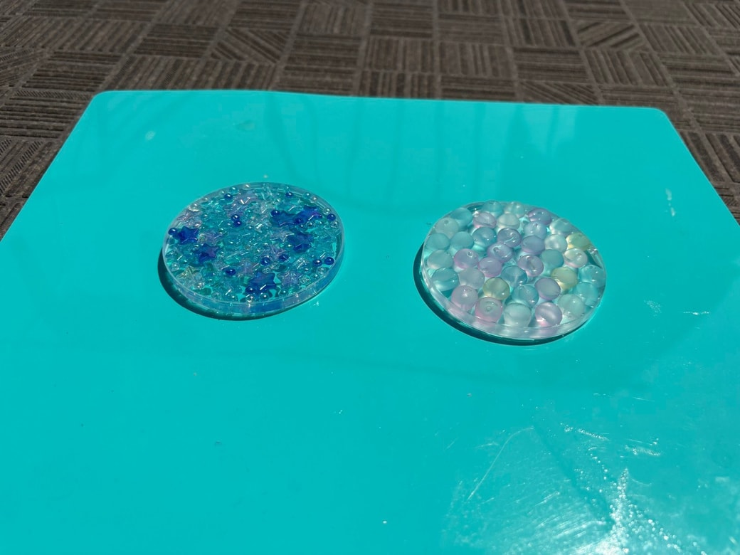 プリングルズのふたにのりと飾りを入れたものを日光で乾かしている様子