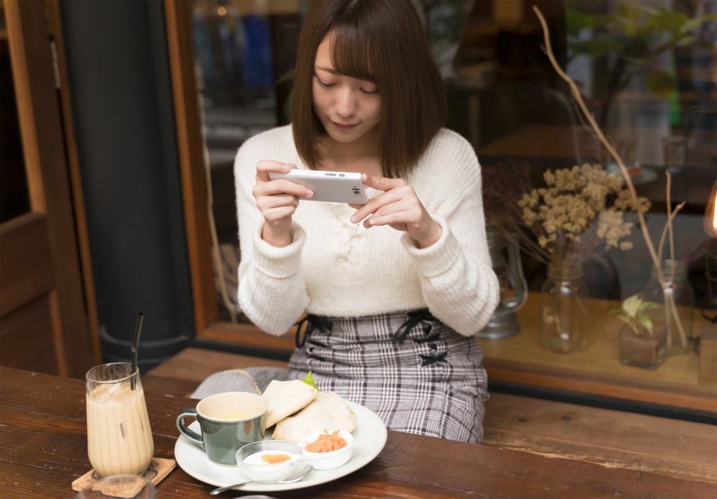 カフェで料理の写真を撮る女性