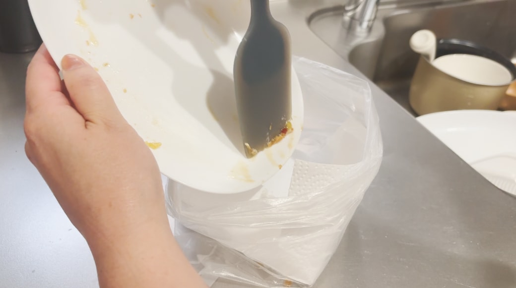 お皿のソース汚れをヘラで落とす