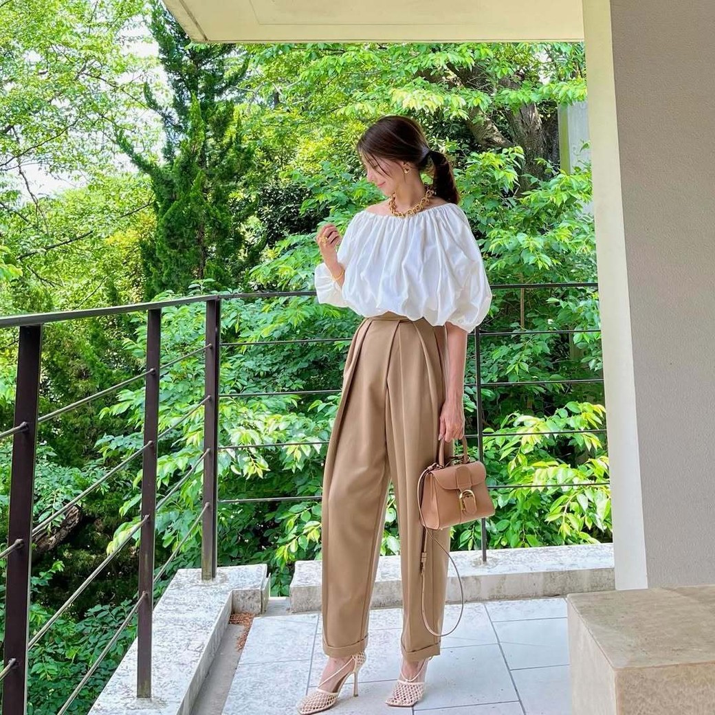 タック入りのベージュパンツはフェミニンなアイテムともバランスよし。