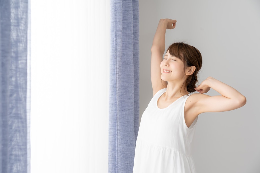 窓際で伸びをする女性