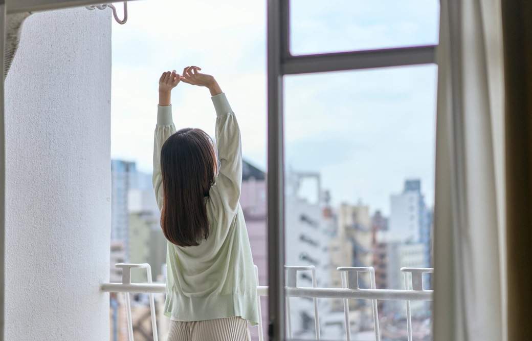 ベランダで伸びをする女性
