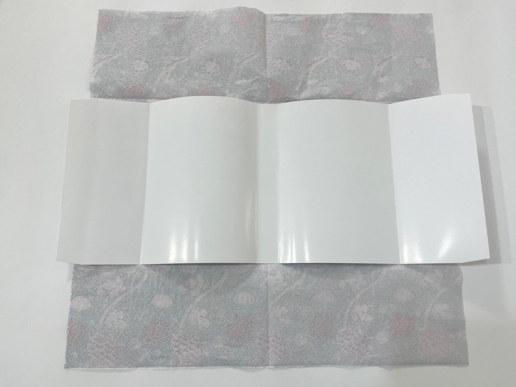 ペーパーナプキンを裏返して広げ、その中央に元のカバーを置く
