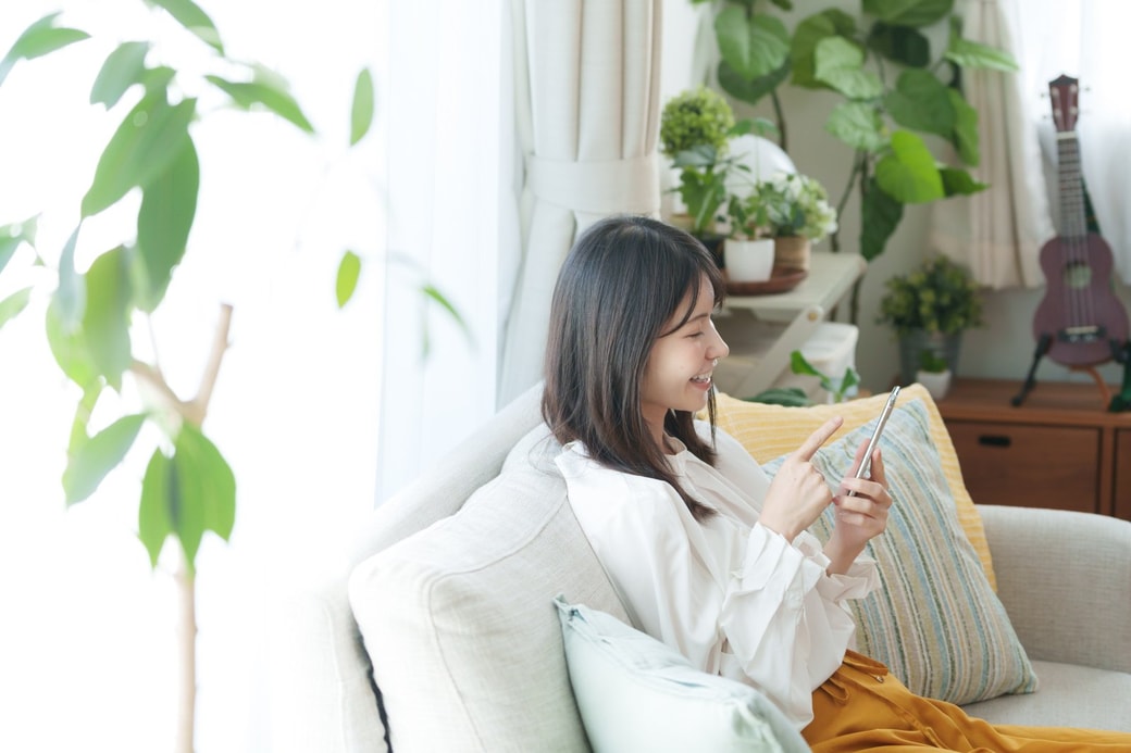 リビングでスマホを見る女性
