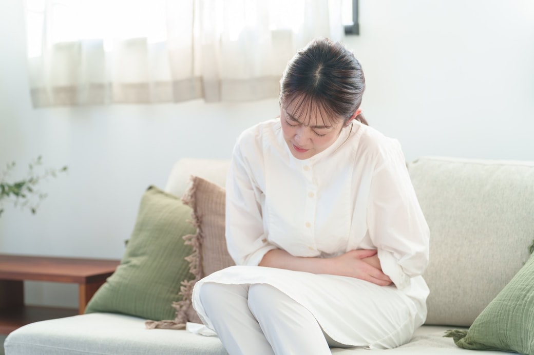 お腹を抑えて苦しむ女性