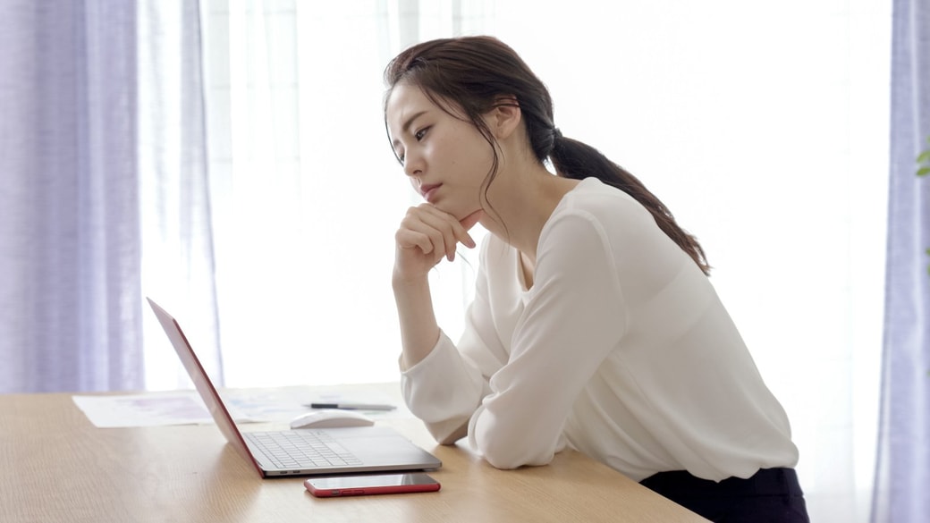 PC画面を前に悩む女性