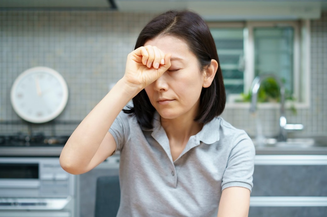 頭痛で頭を押さえる女性