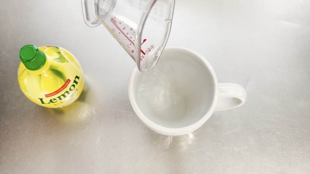 マグカップの水にレモン果汁を加える