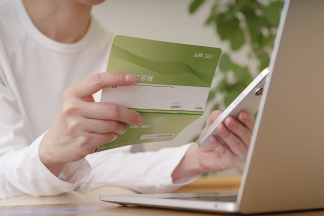  スマホと通帳で金銭のやり取りをする女性