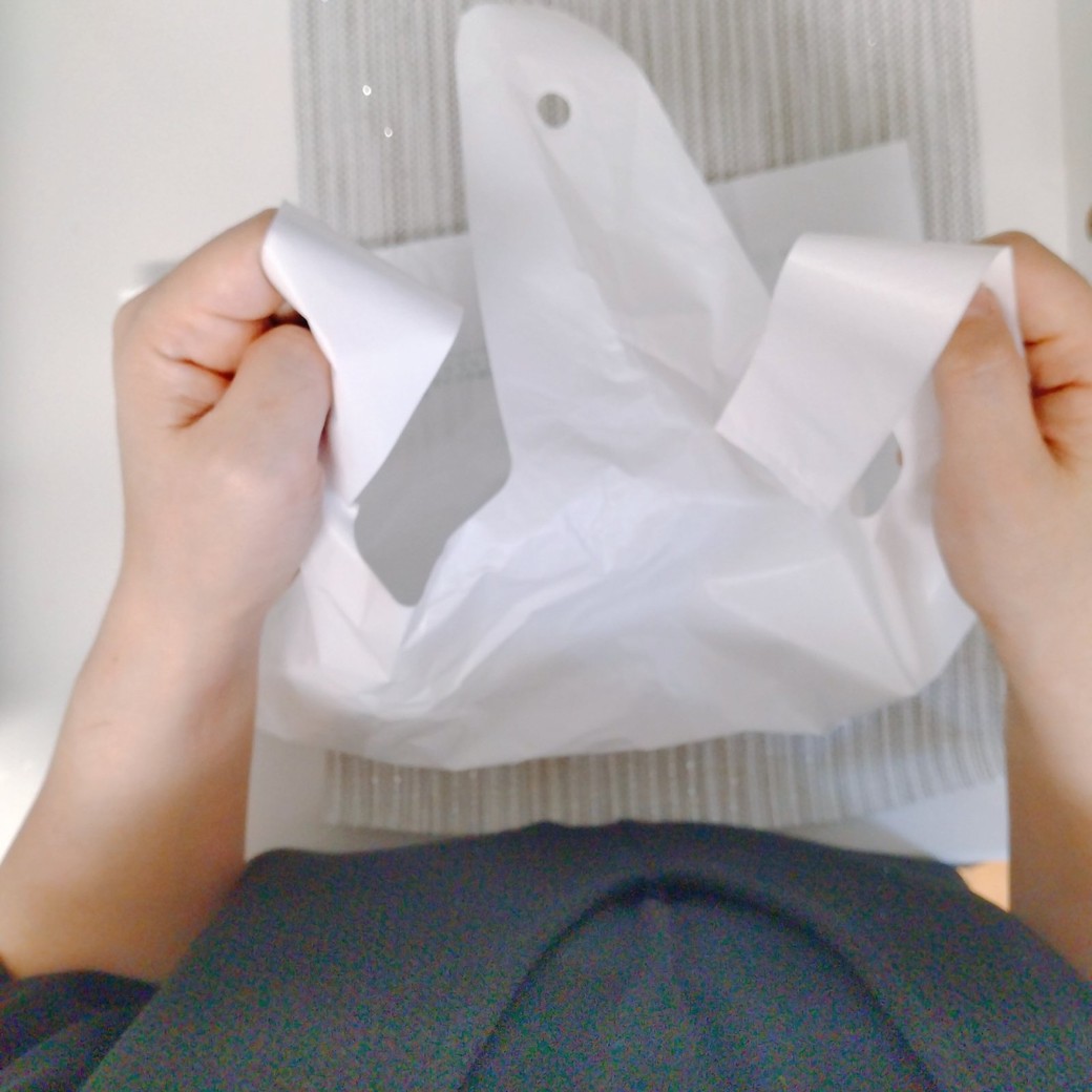 スーパーの袋を手で持つ人