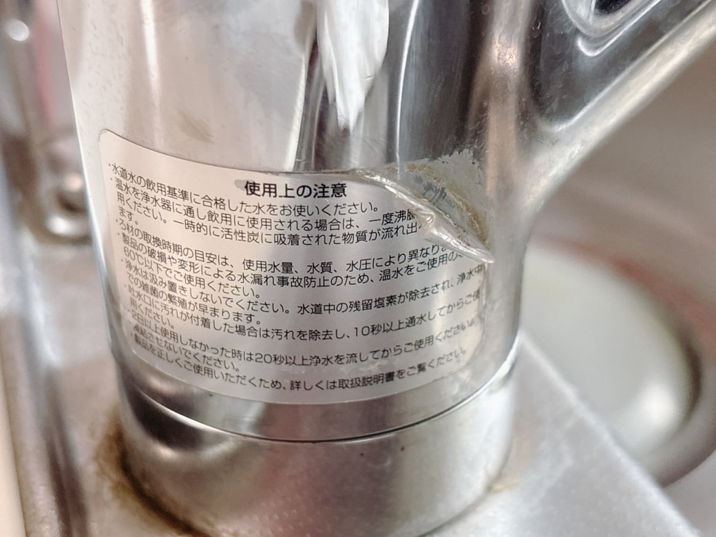 水栓に貼られた、めくれかかっている注意書きシール