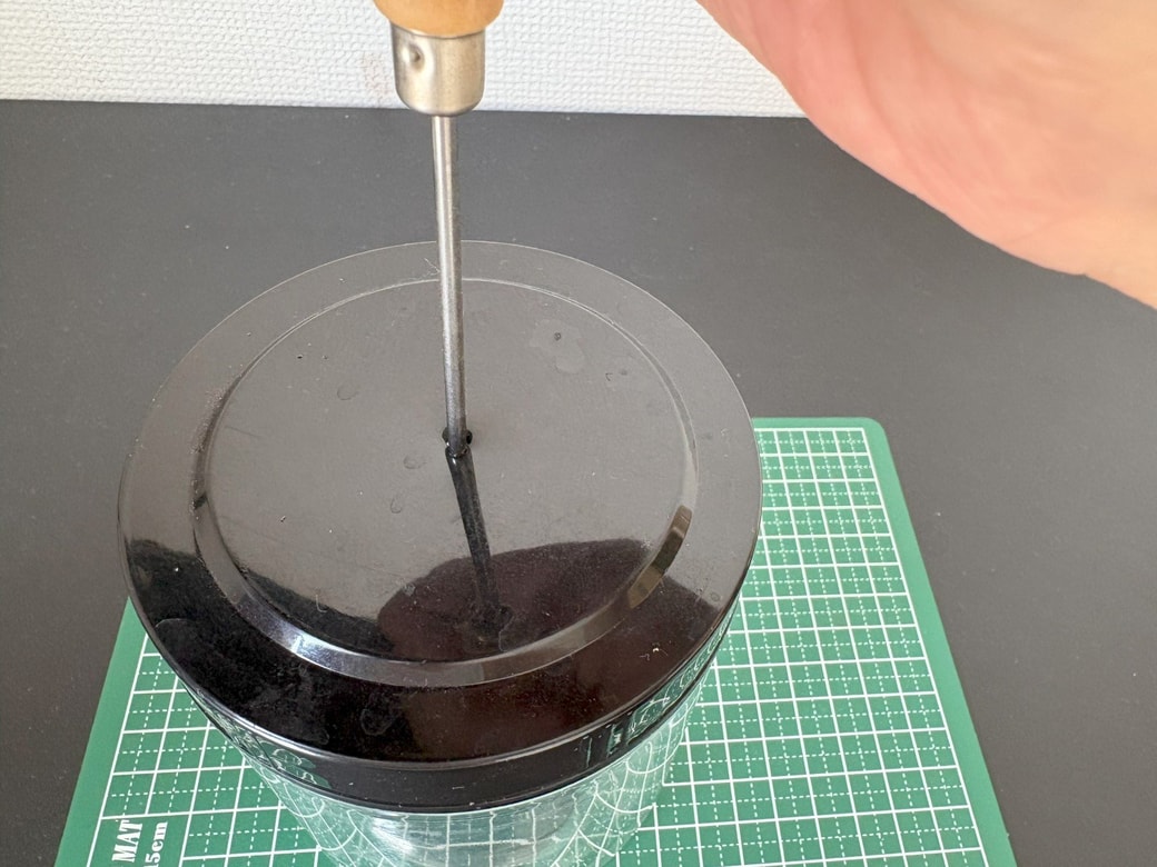 ふたに千枚通しで穴を開ける様子