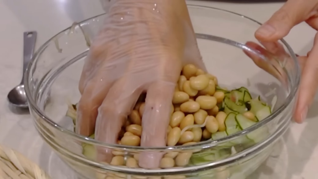 大豆をボウルに加える人