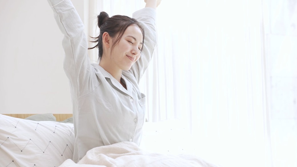 起きて伸びをする女性