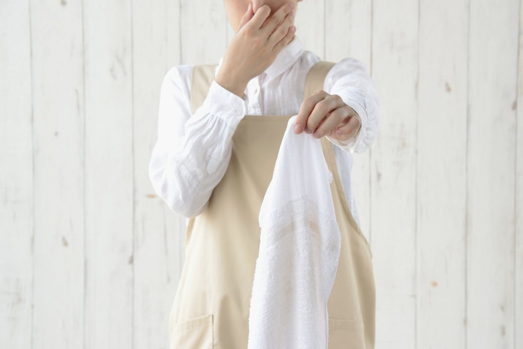 タオルの臭いに鼻をつまむ女性