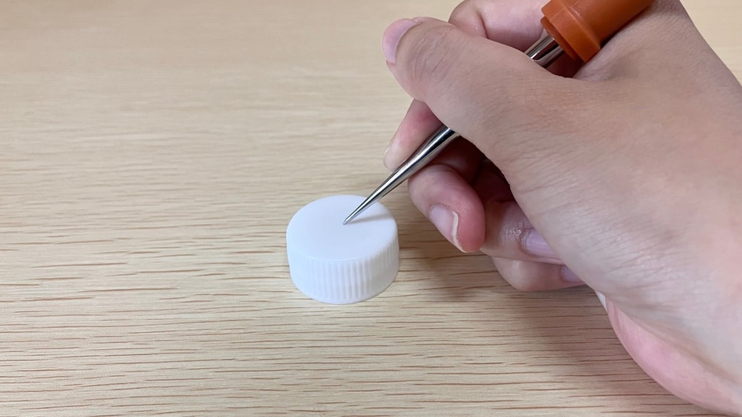 ペットボトルのフタに穴を開ける様子