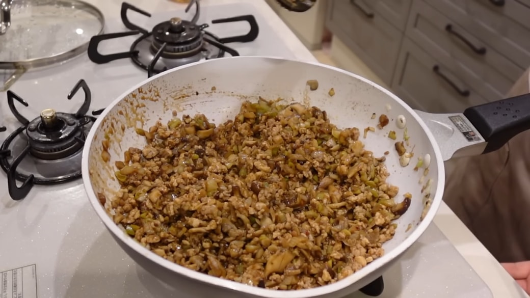 フライパンにきのこや鶏ひき肉を炒める人