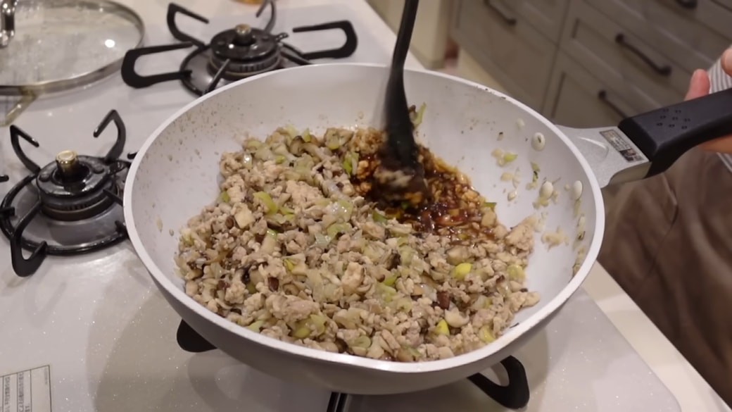 フライパンにきのこや鶏ひき肉を炒める人