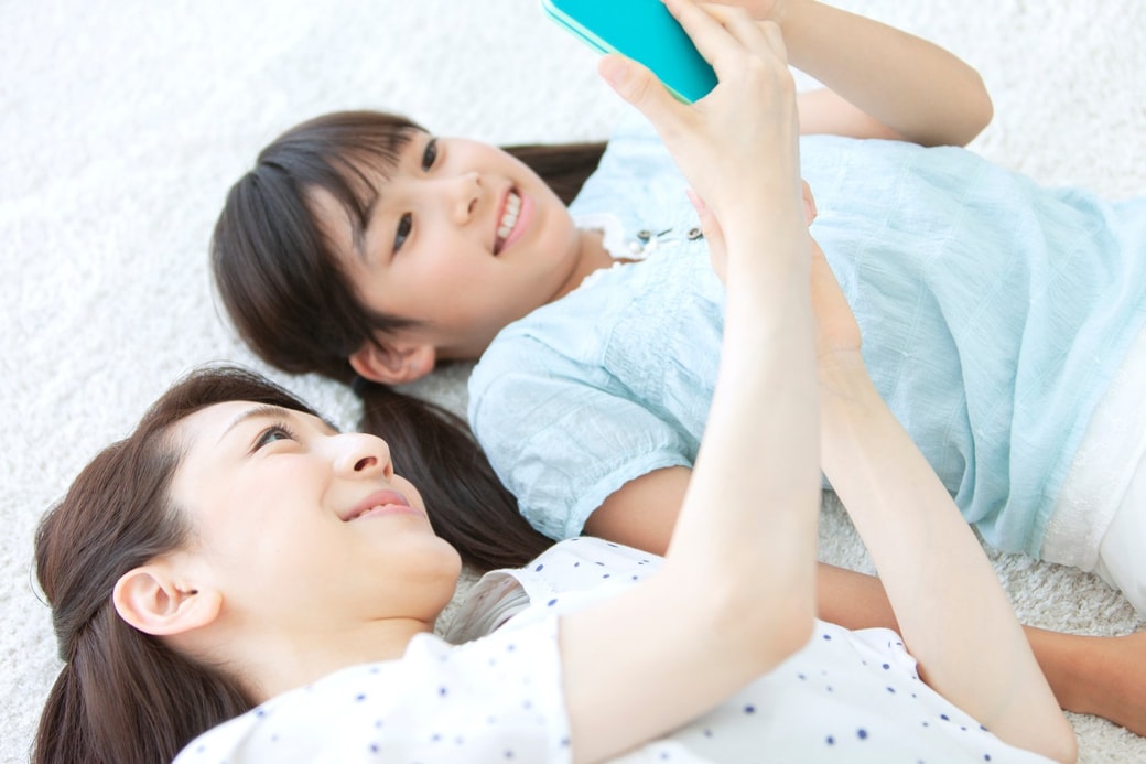 笑顔でスマホを見る親子