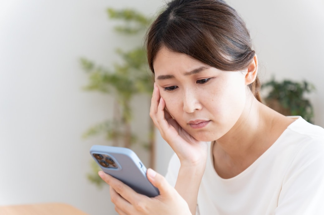スマホを見て悩む女性
