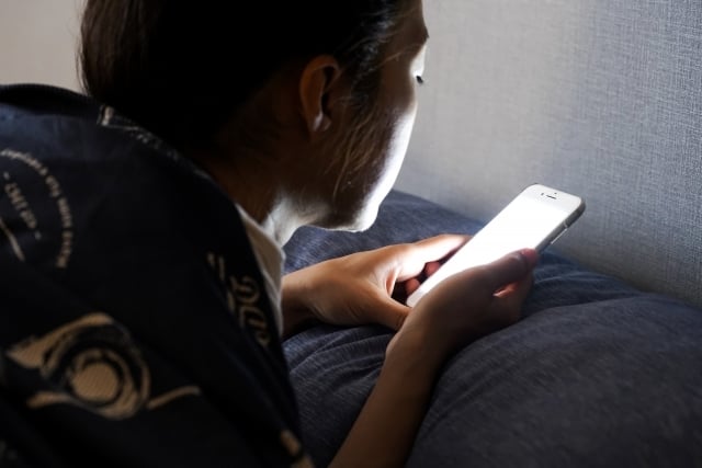 夜中にスマホを見る女性