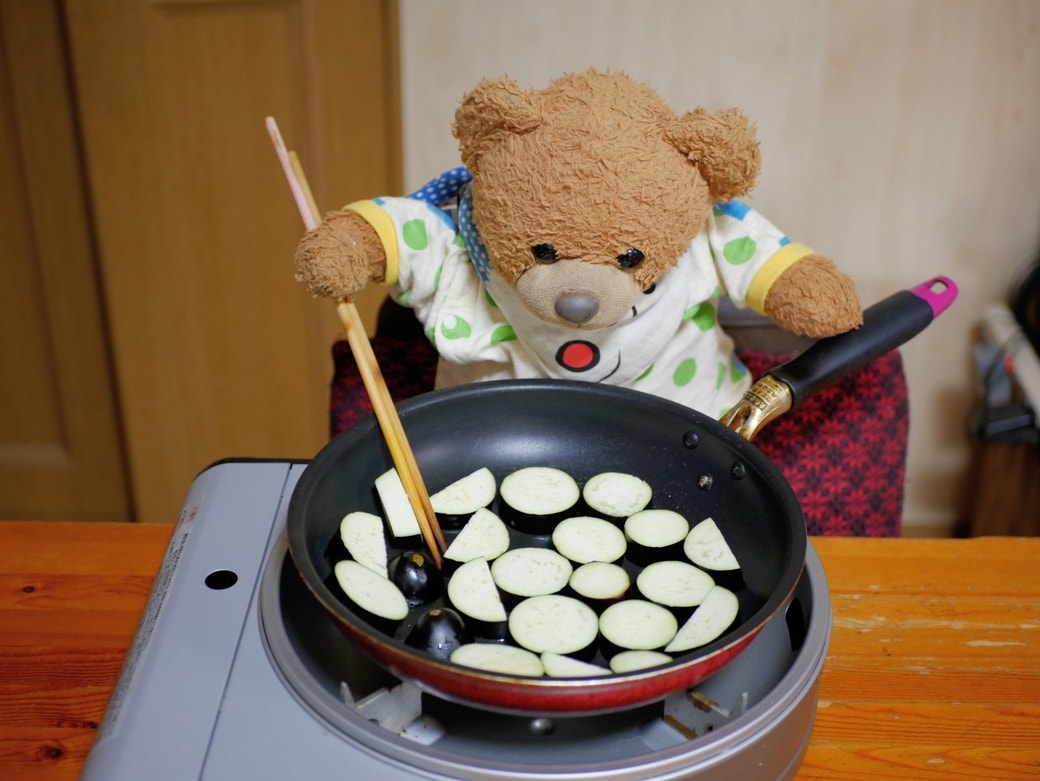 茄子を炒め始めるくまくん