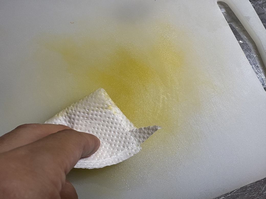 キッチンペーパーでまな板をこする様子
