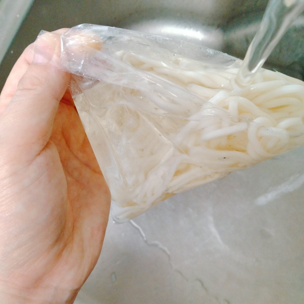うどんが入った袋に水を入れる人