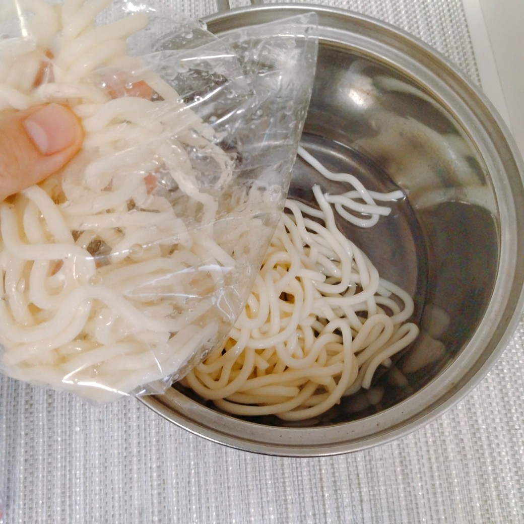 袋に入ったうどんをだす人