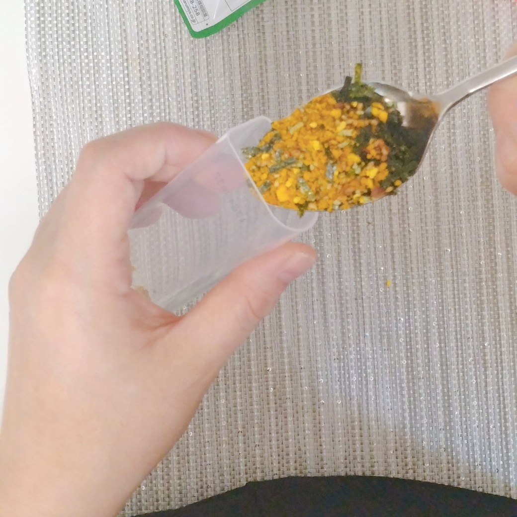 チョコベビーの空き容器にふりかけを入れる人