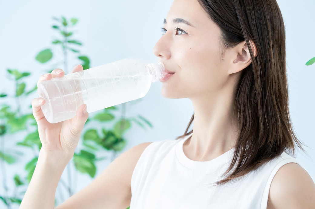 ペットボトルの水を飲む女性