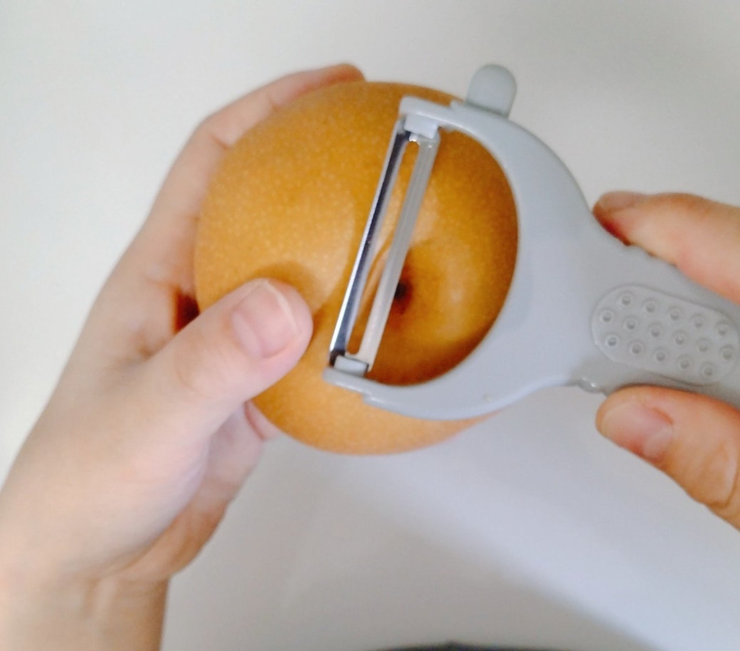 ピーラーで梨の皮を剥く人
