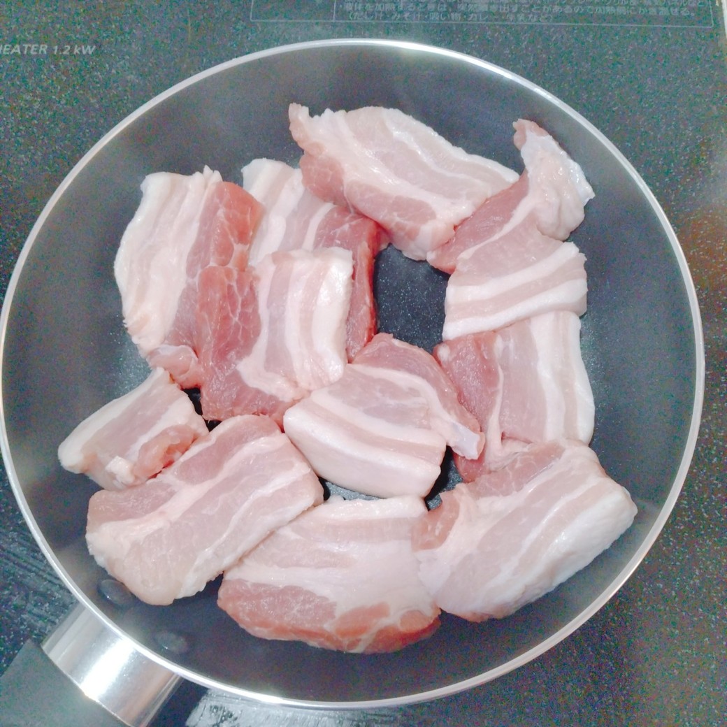 フライパンで豚肉を焼く人