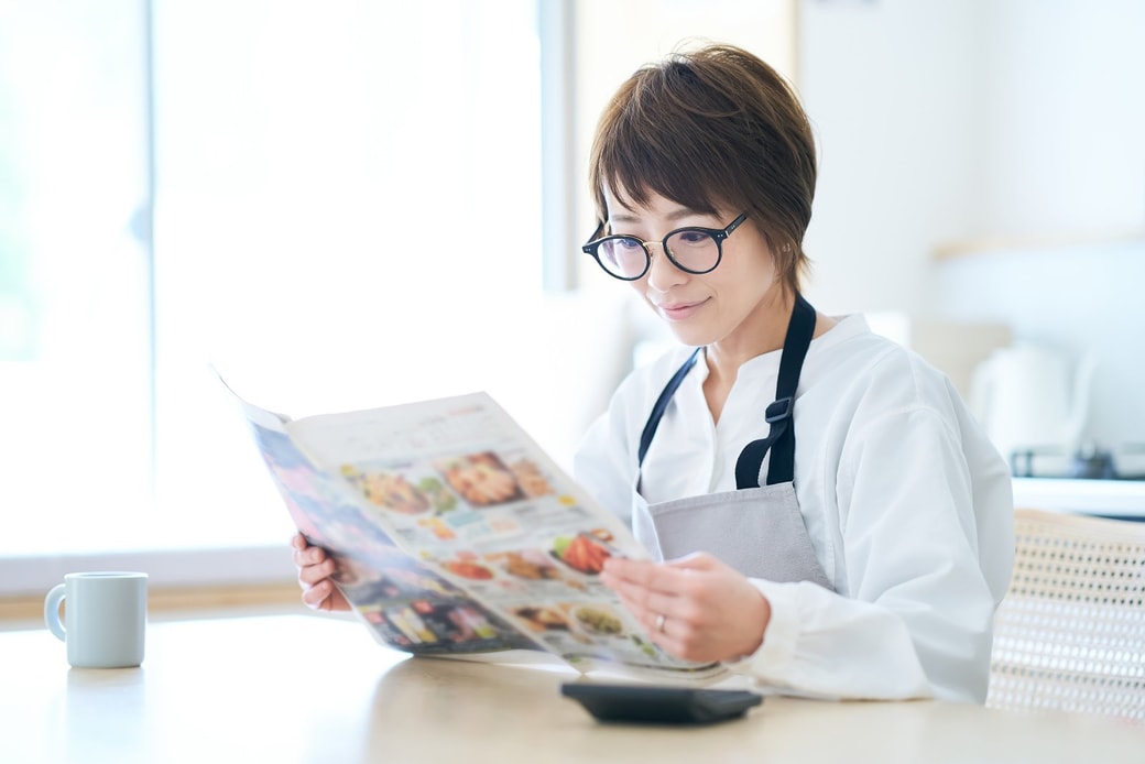 スーパーのチラシを見る主婦