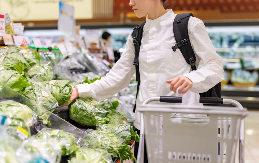 スーパーの野菜売り場をまわる女性