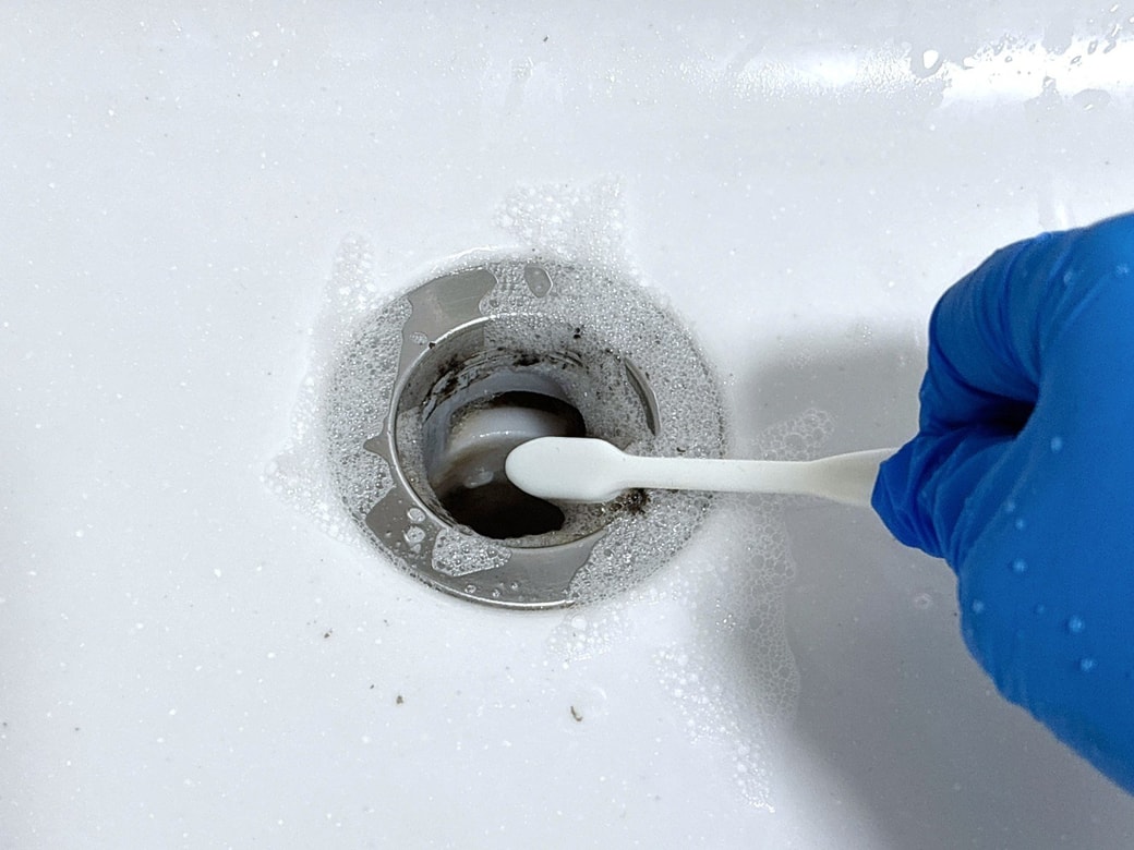排水口の汚れを歯ブラシで落とす