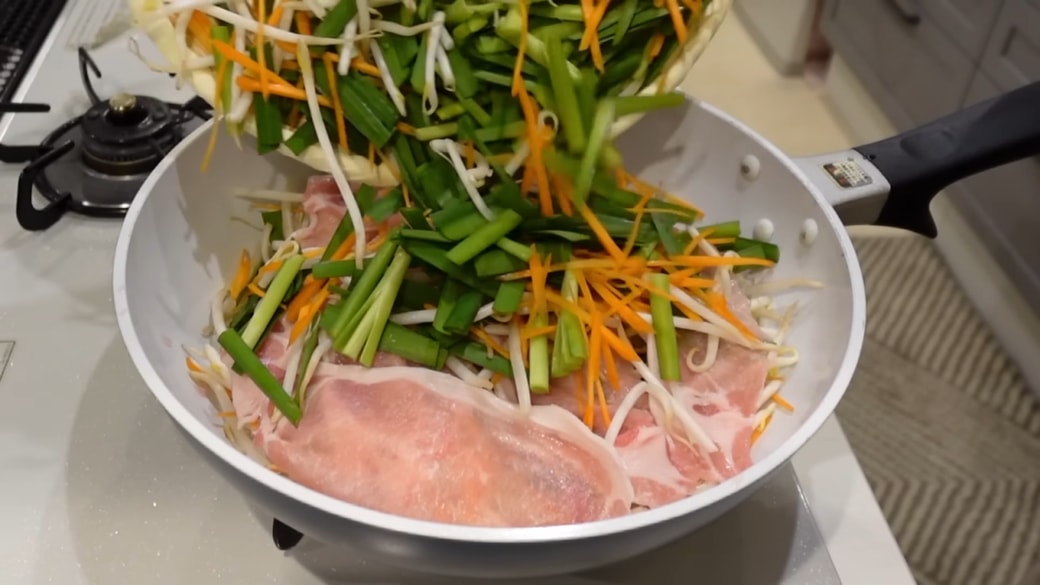 野菜をフライパンに入れる人