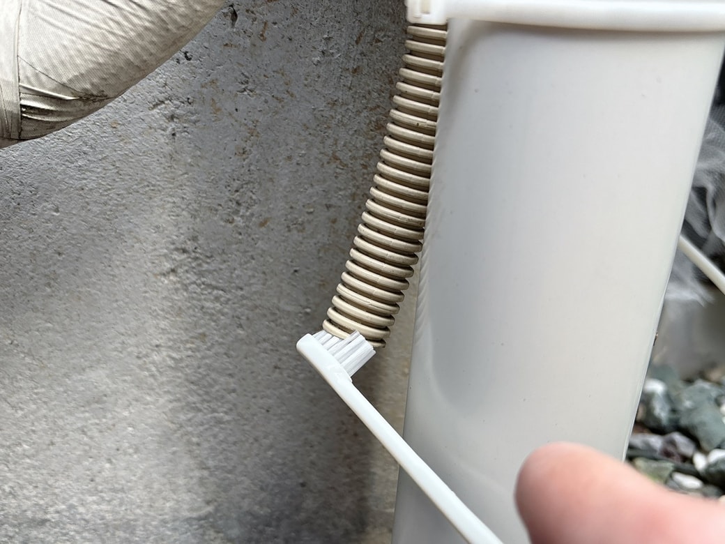 ドレンホースの汚れを歯ブラシで取り除く