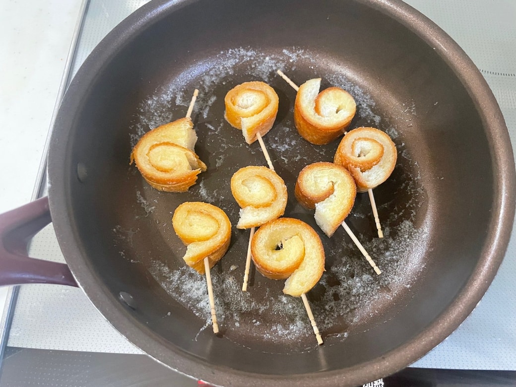 フライパンにバターを入れて巻いたパンの耳を焼く