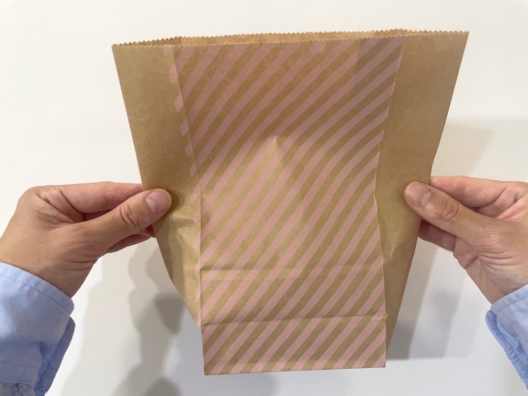 紙袋の上部のマチを広げて平らにする