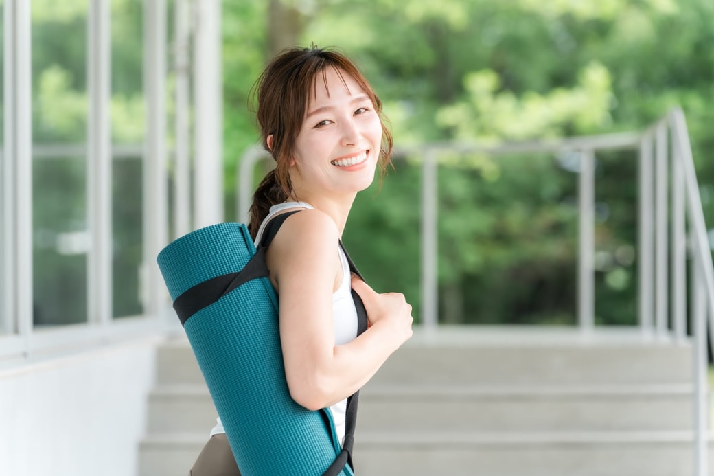 ヨガマットを持つ女性