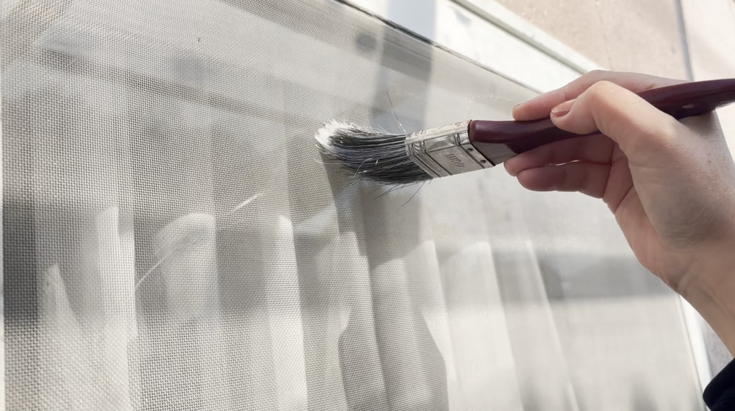 ハケを使って網戸の砂埃を落とす