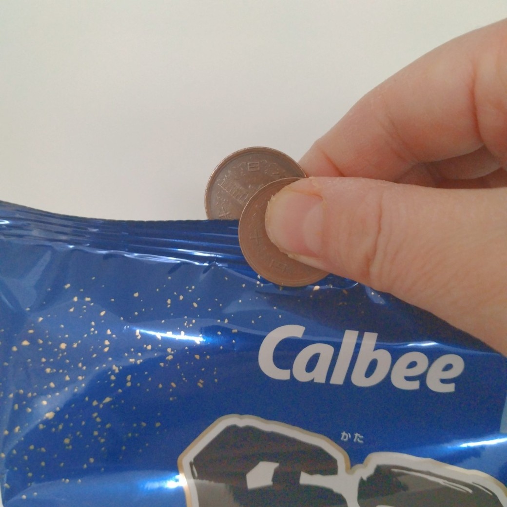 10円玉でお菓子の袋をはさむ人