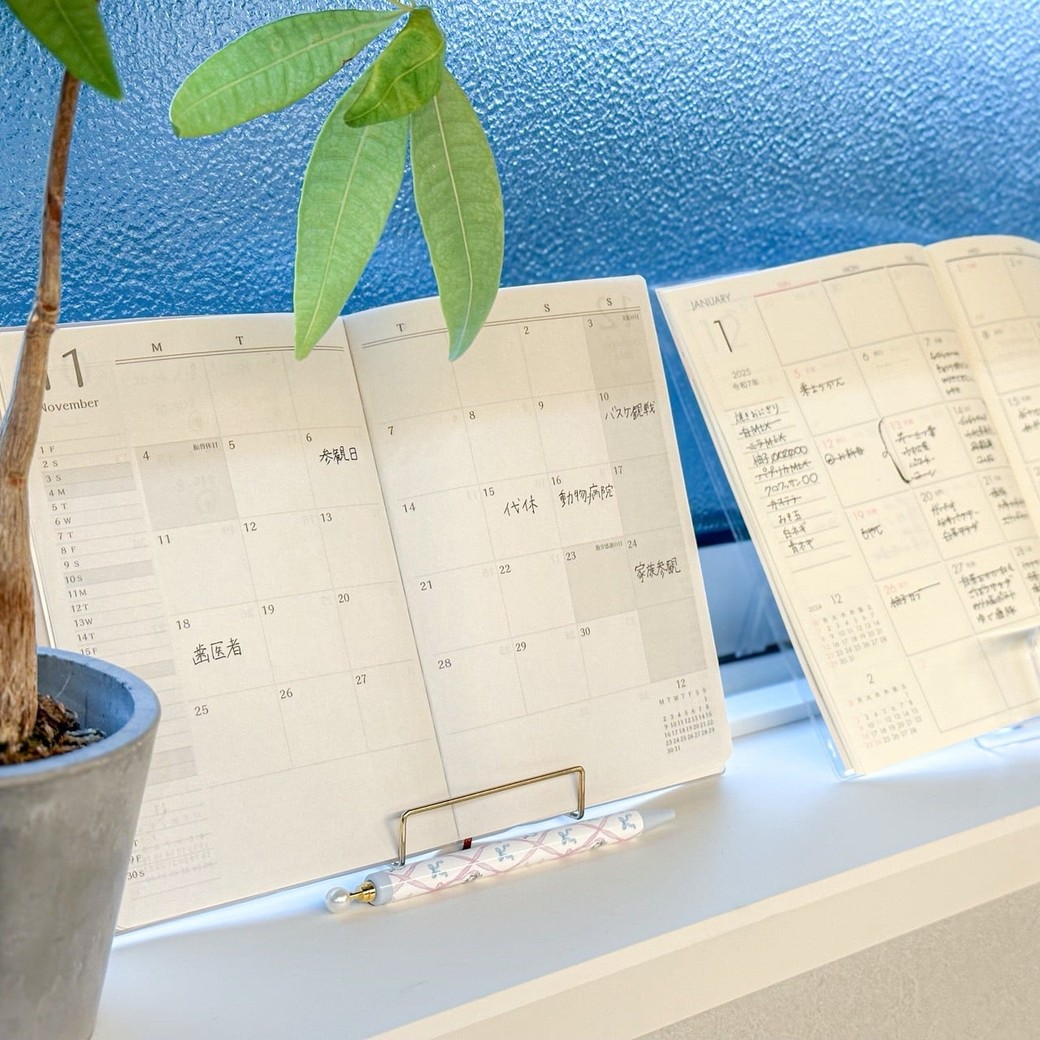 ワイヤーイーゼルに立てかけられた薄型マンスリー手帳。見やすく省スペースな設置方法。