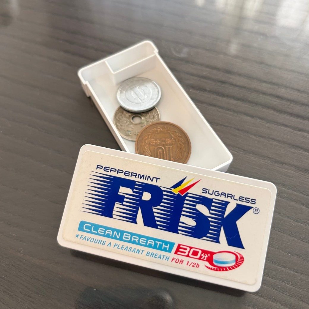 フリスクの容器に小銭を入れているところ